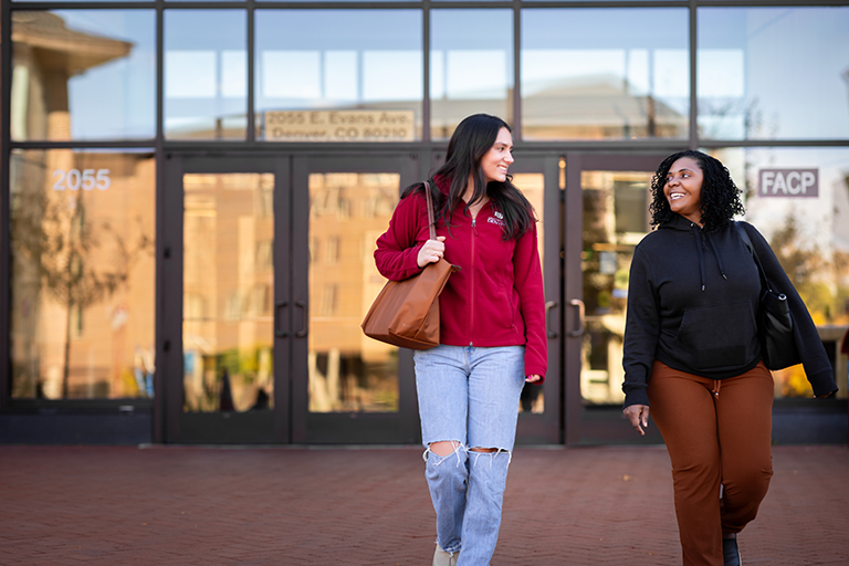 two women walk and talk outside of Community Commons
