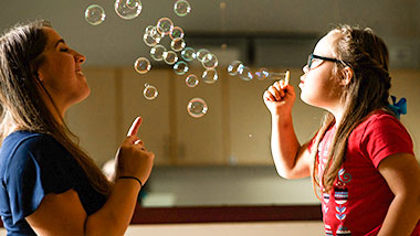 chlid blowing bubbles with counselor