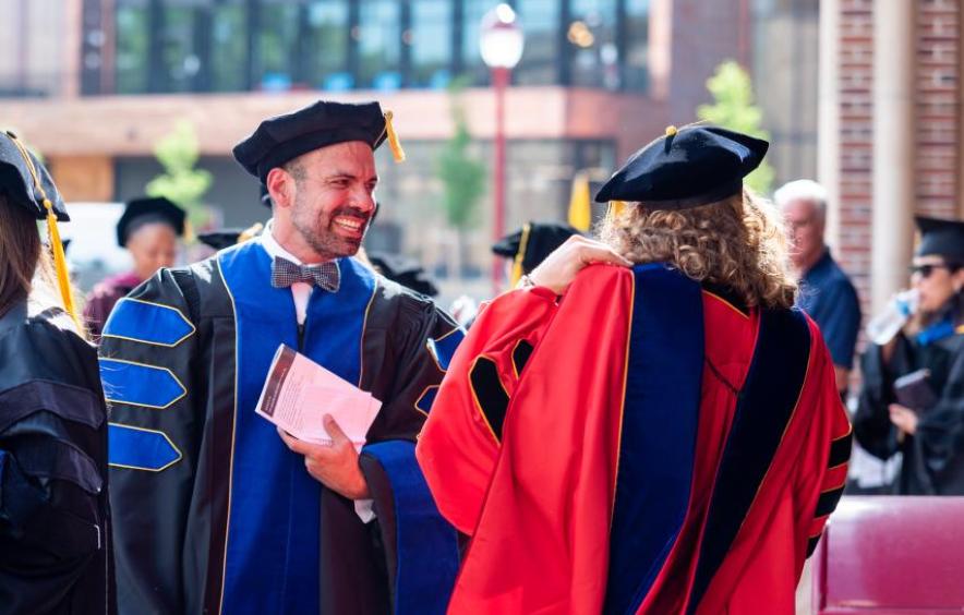 Graduate and faculty talking and smiling