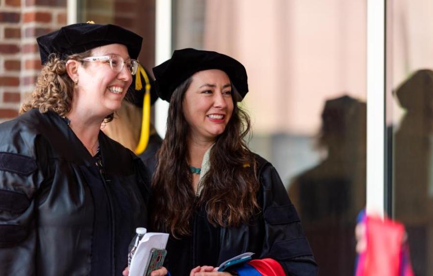 Two doctoral graduates smiling