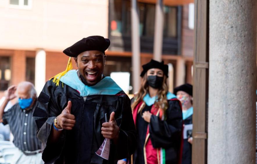 Doctoral grad giving thumbs up