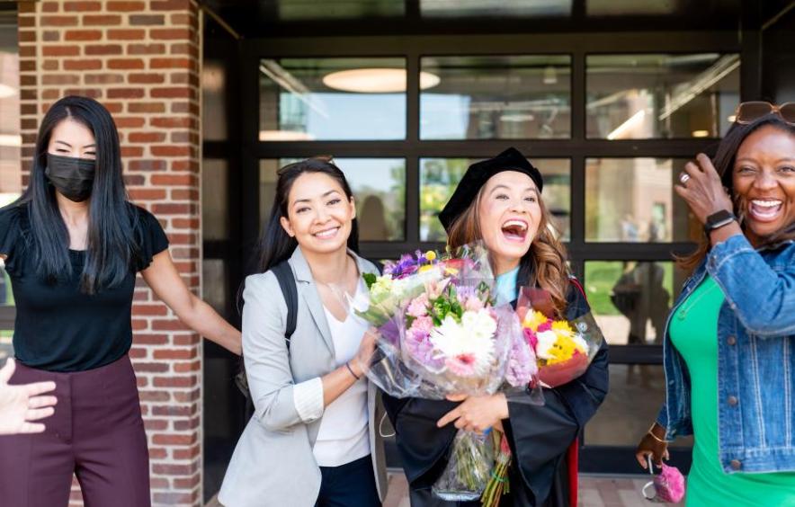 Hooding ceremony photo featuring graduate holding flowers
