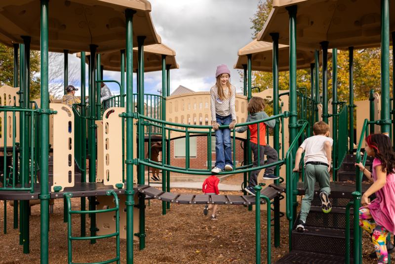 Children playing and climbing on a school playground structure outdoors.
