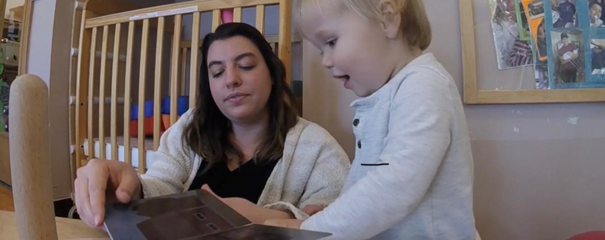 Caregiver reads book with child.