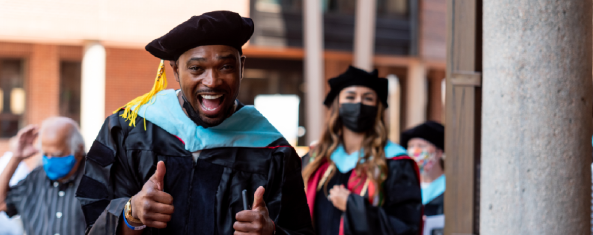 MCE doctoral student giving thumbs up and smiling at hooding ceremony