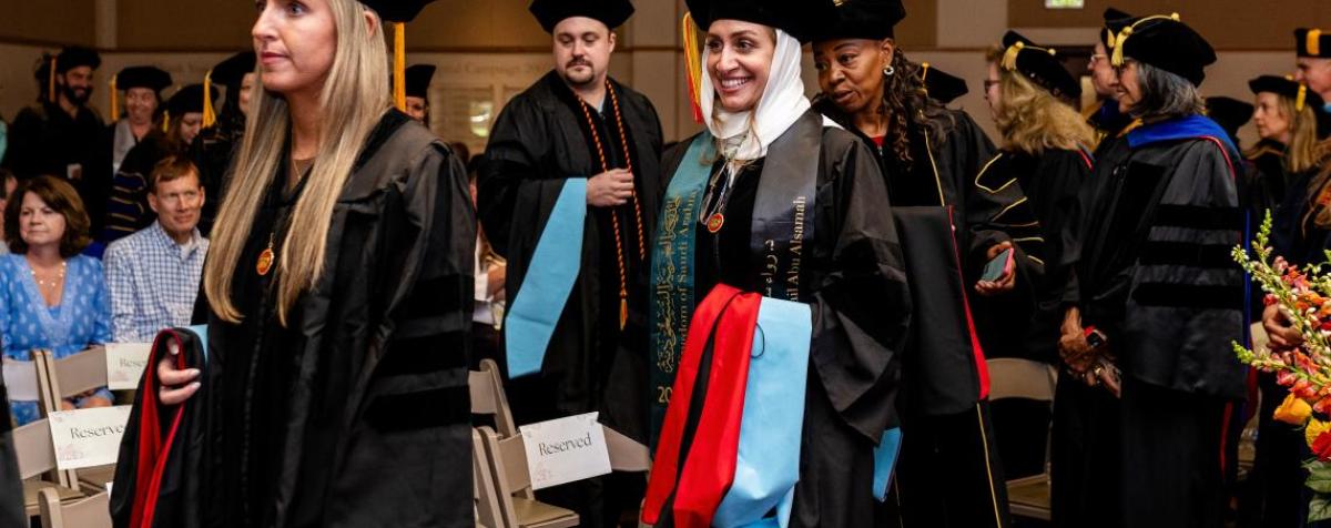 students walking through hooding ceremony